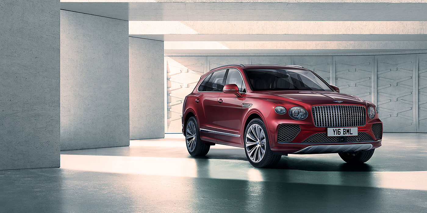 Jack Barclay Bentley Bentayga Atelier Edition SUV in Rubino Red paint front three quarter against textured concrete wall