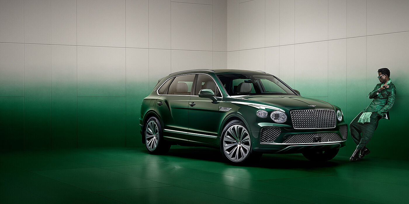 Jack Barclay Wisdom K leans against wall next to Bentley Bentayga Extended Wheelbase Atelier Edition SUV in Light Emerald green paint