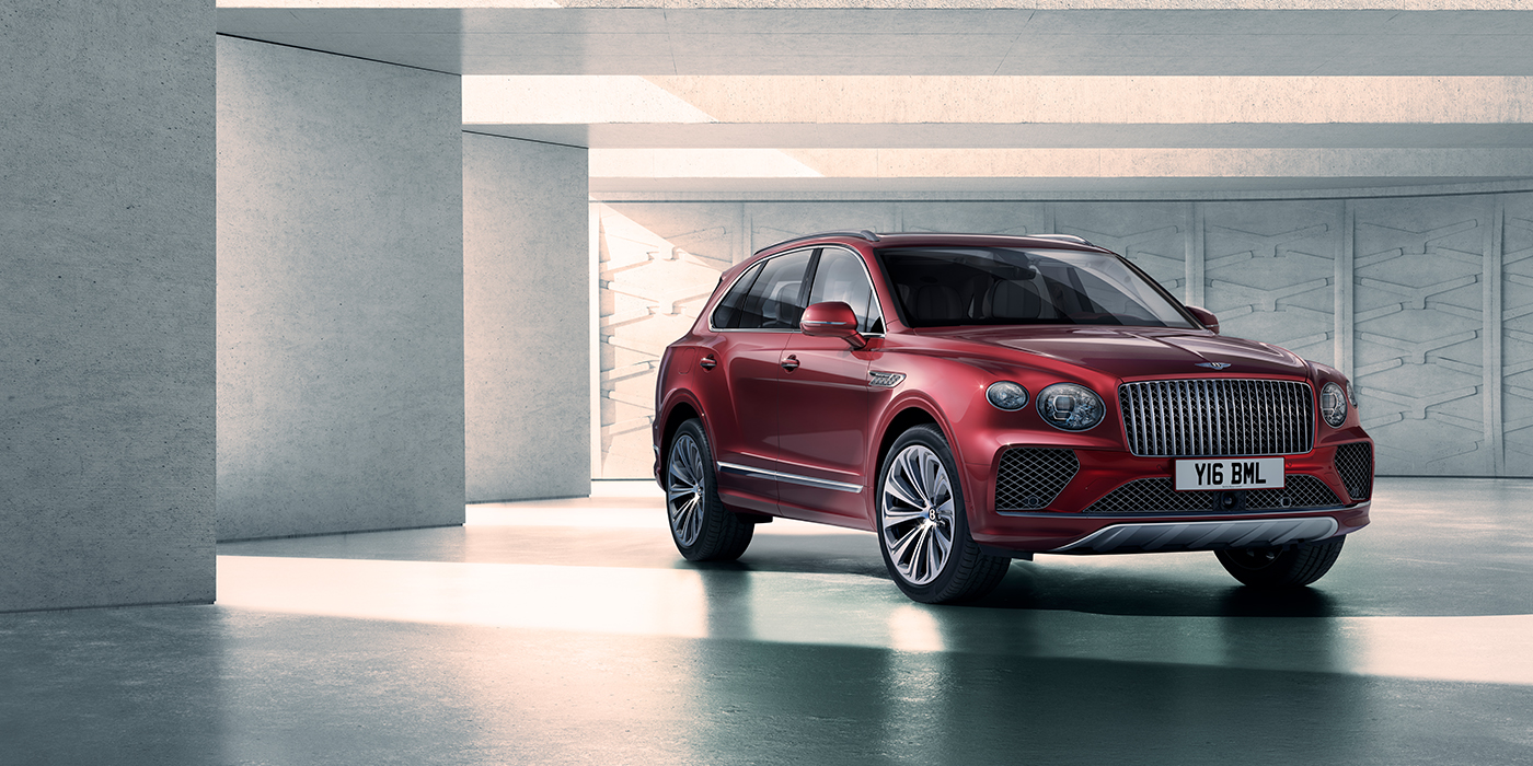 Jack Barclay Bentley Bentayga Atelier Edition SUV in Rubino Red paint front three quarter against textured concrete wall