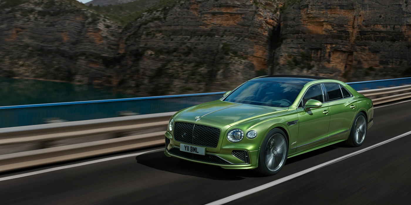 Jack Barclay Bentley New Flying Spur Speed v8 hybrid sedan driving dynamically on a mountain road in Tourmaline Green paint