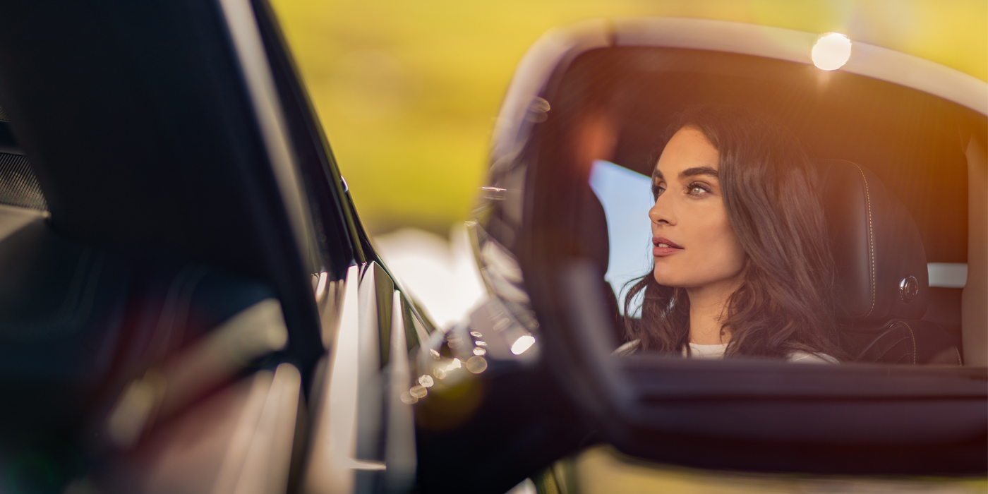 Jack Barclay profile of dark haired woman's face in mirror of Bentley car in sunlight
