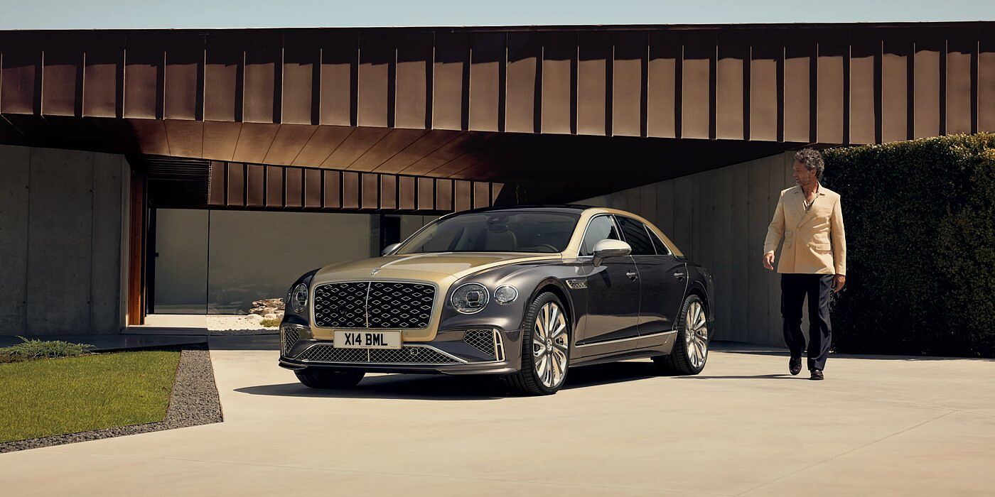 Jack Barclay Bentley New Flying Spur Mulliner V8 hybrid sedan front three quarters in Rose Gold over Magnetic paint, parked near modern home