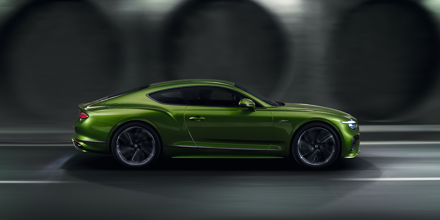 Jack Barclay Bentley Continental GT coupe in Tourmaline Green paint driving in profile on a dark road