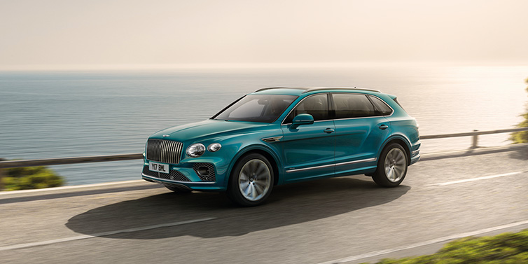 Jack Barclay Bentley Bentayga Extended Wheelbase Azure SUV in Topaz blue paint driving dynamically by the ocean