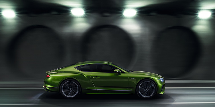 Jack Barclay Bentley Continental GT Speed coupe profile in Tourmaline Green driving dynamically past a concrete wall at night