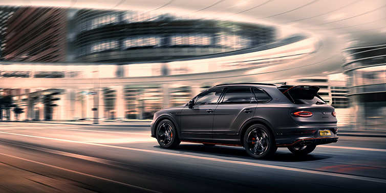 Jack Barclay Bentley Bentayga S Black Edition SUV rear three quarter in Anthracite Satin paint driving dynamically through a city at night