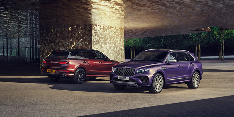 Jack Barclay A duo of Bentley Bentayga Extended Wheelbase Mulliner SUVs parked in a city environment, with Tanzanite Purple and Cricket Ball red exterior paint