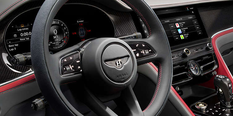 Jack Barclay Bentley Flying Spur Speed sedan front interior detail showing steering wheel and driver screens surrounded with Hotspur red and Gravity Grey hides